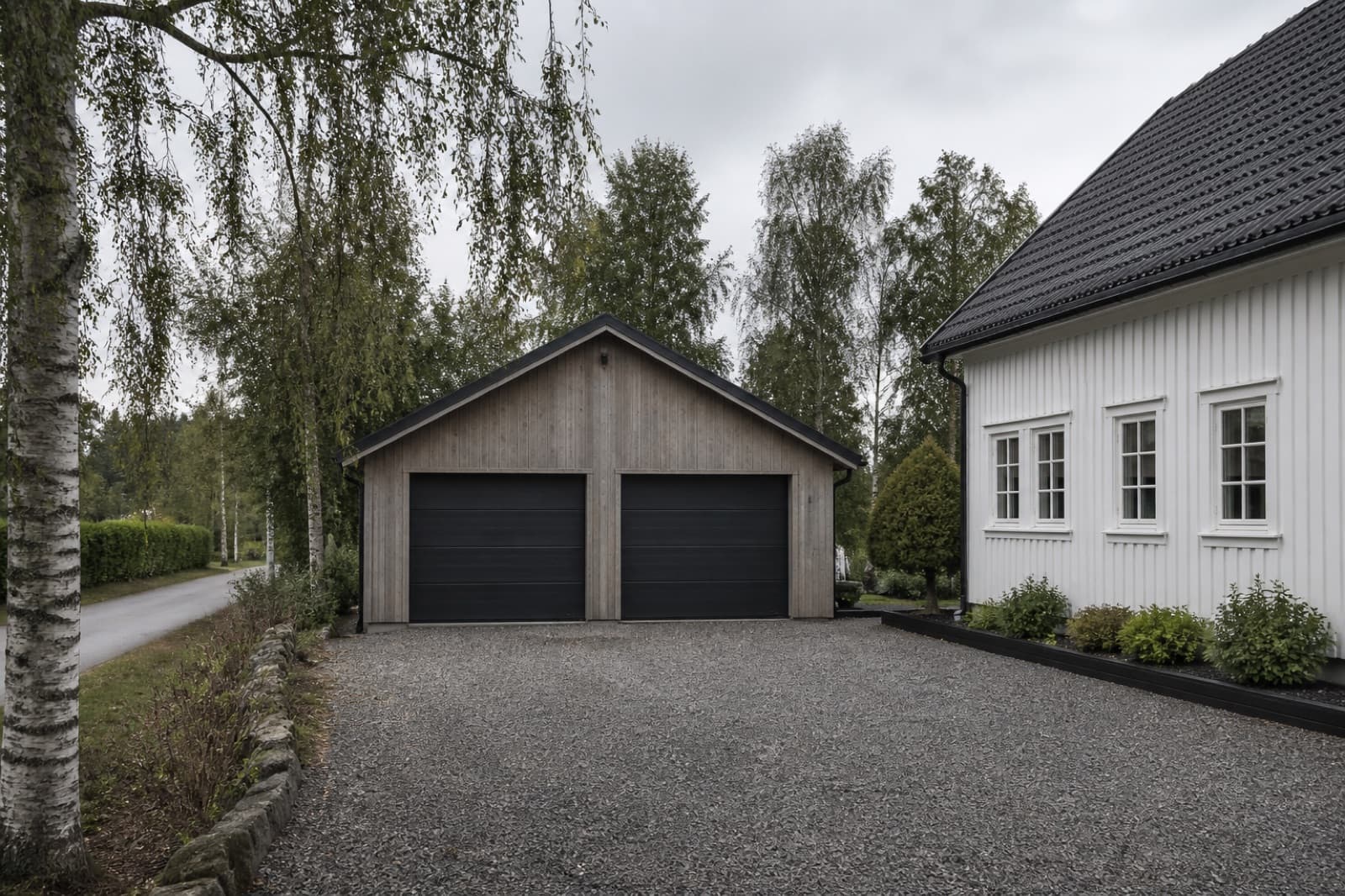 Tregarasje ved siden av en hvit enebolig i et norsk boligområde