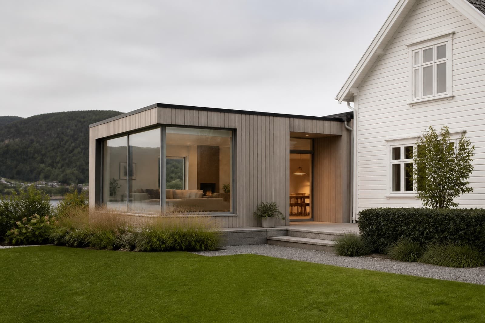 Moderne tretilbygg inntil en eldre hvit enebolig