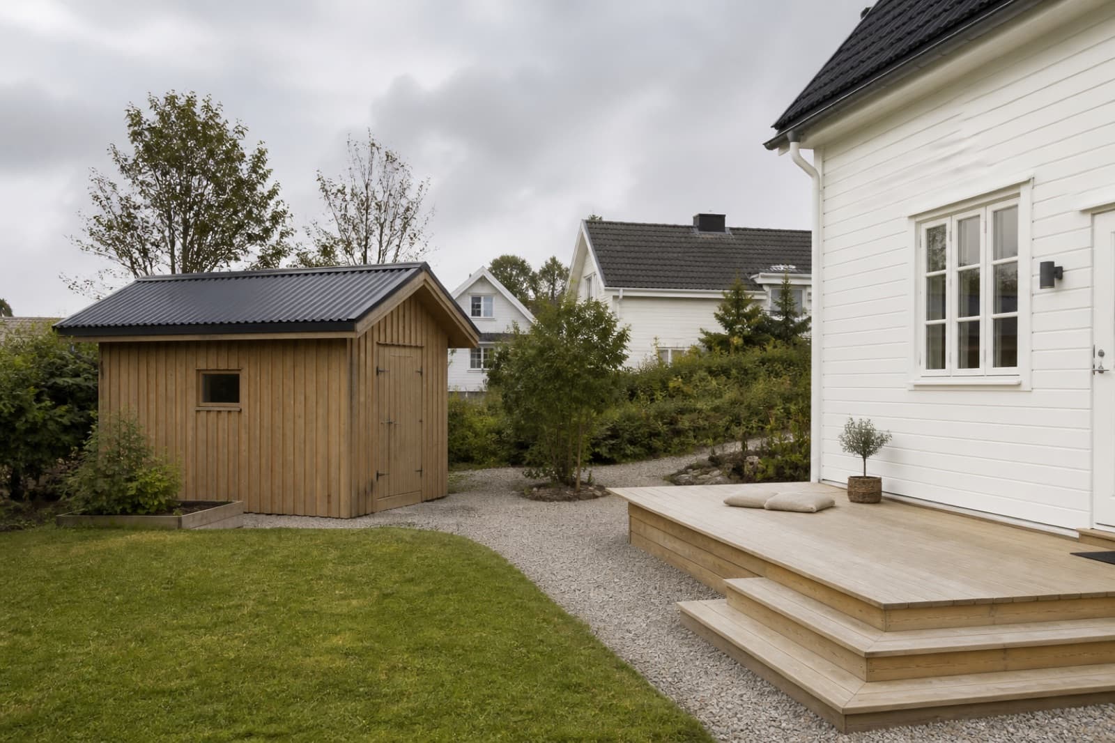 Liten hagebod og enkel treterrasse bak en enebolig